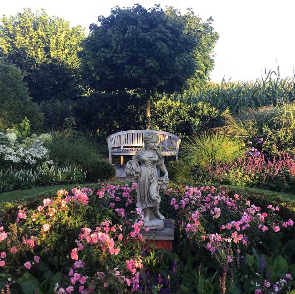 english flower garden young girl statue park bench pink flowers