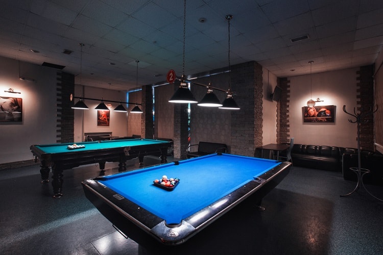 large entertainment room two billiard tables track lighting black sofa 