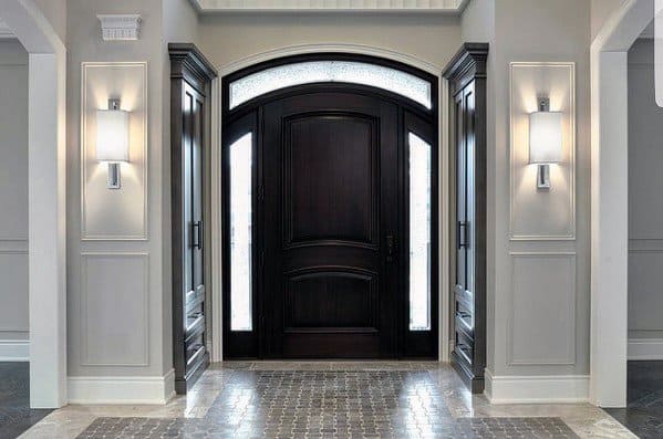 Modern entryway with dark wood door, arched transom, and gray panelled walls.