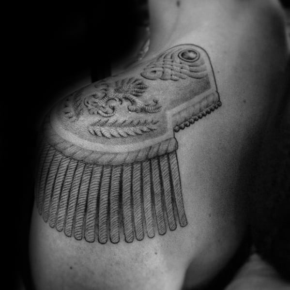 Realistic epaulette tattoo with fine ornamental embroidery, textured braids, and straight tassels flowing over the upper arm.