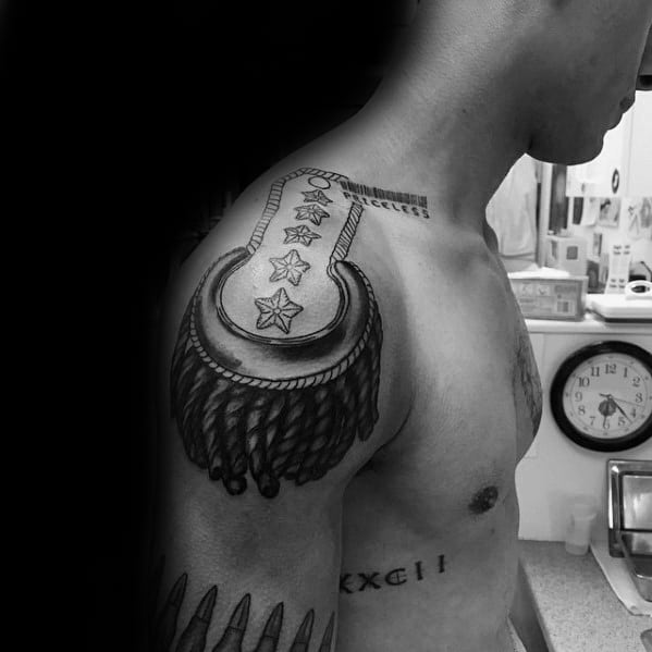 Military-style epaulette tattoo with three stars, braided border, and dark tassels cascading over the shoulder.