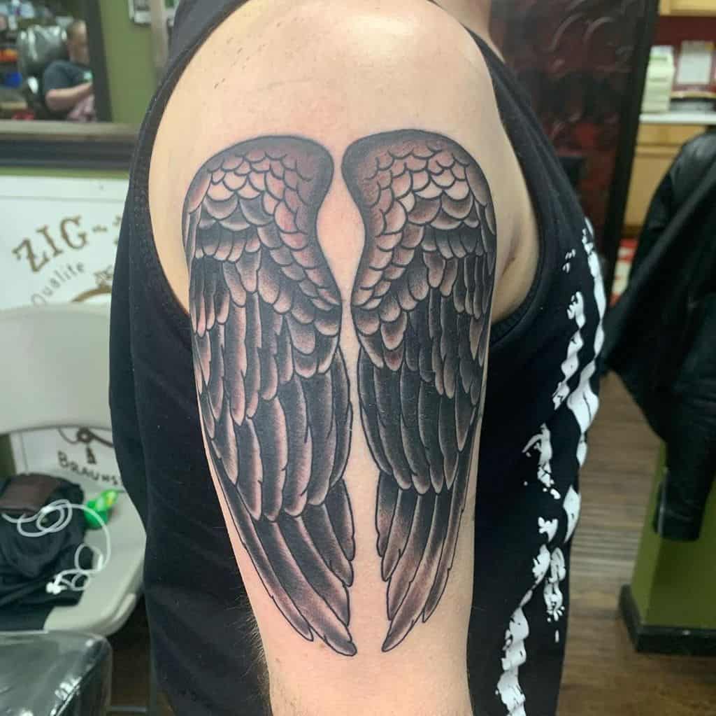 A tattoo of angel wings, depicted with detailed feathers in shades of black and gray