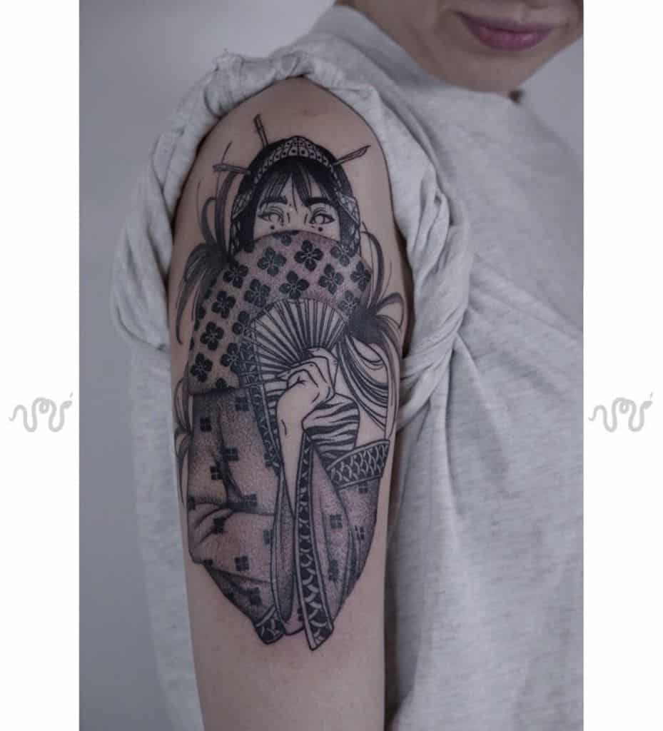 Black ink upper arm tattoo of a Geisha partially covering her face with a floral-patterned kimono and fan, featuring intricate linework and shading.
