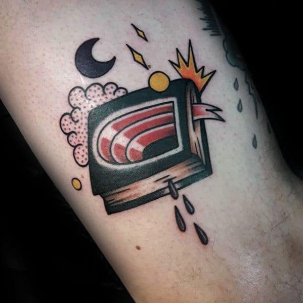 Colorful tattoo of a stylized bleeding TV with a tongue, surrounded by abstract shapes, stars, and a crescent moon.
