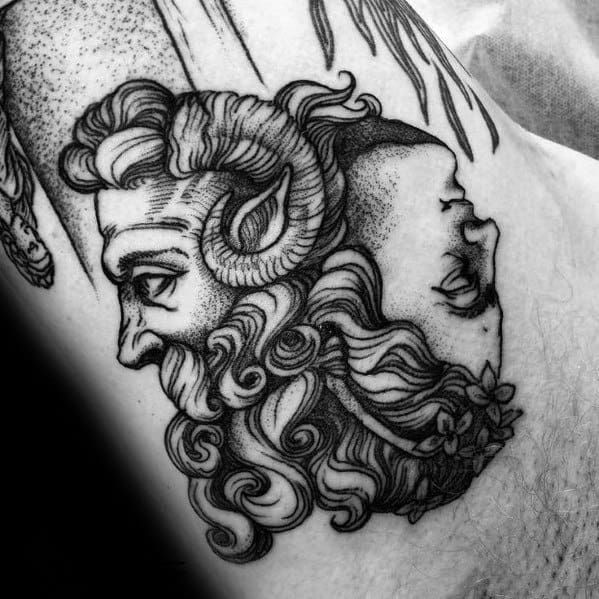 Tattoo of a dual-faced figure with one side depicting a horned mythological being and the other a serene human face with floral details.