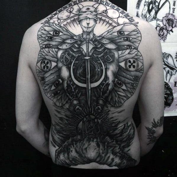 Large back tattoo of a symmetrical figure with a sword, surrounded by wings, geometric shapes, eyes, and surreal organic forms.