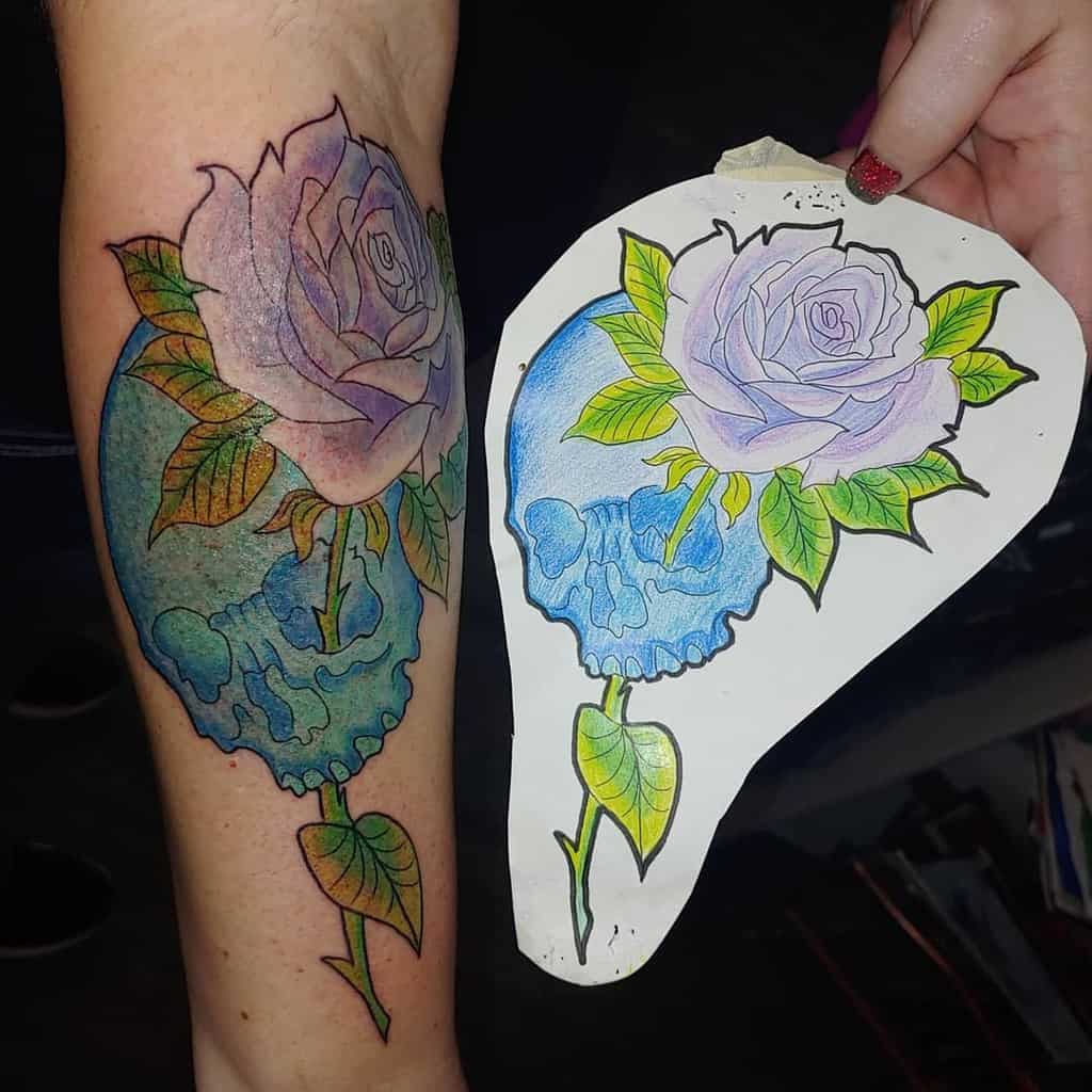 Colorful tattoo of a blue melting skull with a blooming lavender rose, blending surreal and neo-traditional styles on the forearm.