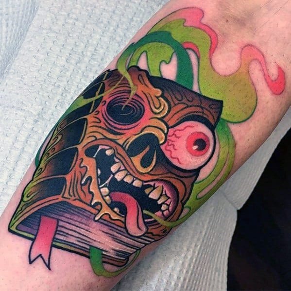 Neo-traditional tattoo of a haunted book with a grotesque skull face, bulging eye, and eerie green smoke for a bold and spooky horror design.