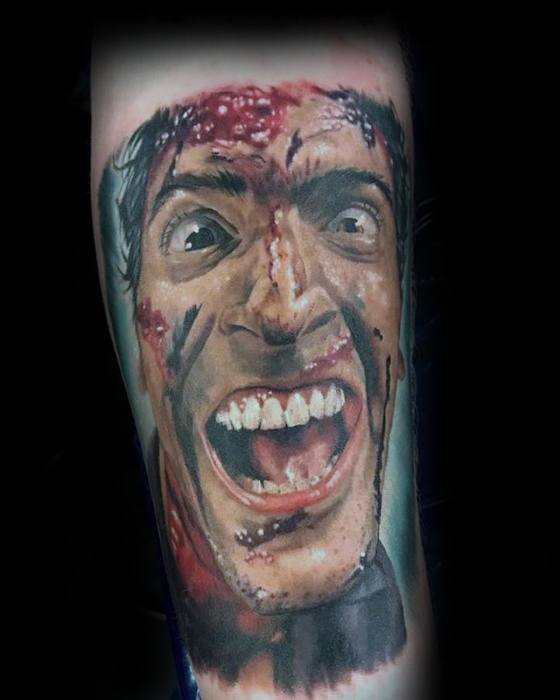 Realistic Evil Dead tattoo of Ash with a crazed, blood-splattered face, wide eyes, and intense grin capturing horror and madness.