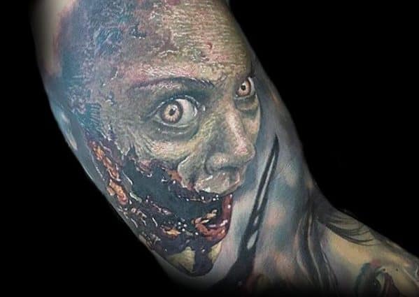 Terrifying Evil Dead tattoo of a possessed woman with rotting flesh, wide glaring eyes, and an eerie smile filled with decay and dread.