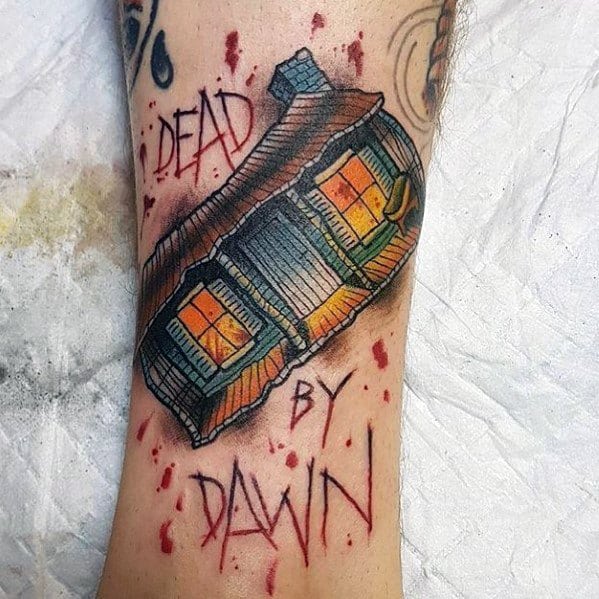 Colorful Evil Dead tattoo of the iconic cabin with glowing windows, blood splatter, and the phrase "Dead by Dawn" in horror-style text.