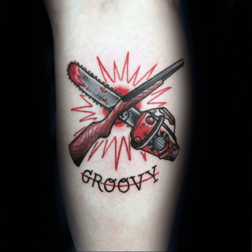 Evil Dead tattoo of a shotgun and chainsaw crossed over a red burst with the word "Groovy" underneath in bold black lettering.