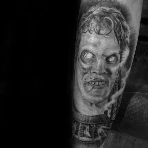 Black and grey Evil Dead tattoo of a possessed figure with glowing eyes and eerie expression, hovering above the haunted cabin.