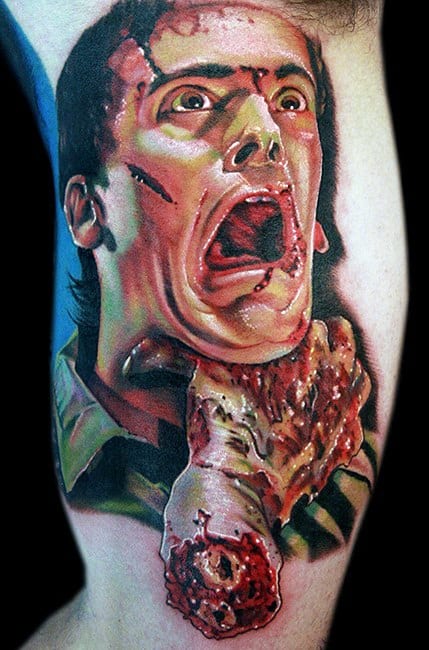 Vibrant Evil Dead tattoo of Ash screaming while being grabbed by a severed hand, showcasing intense horror and blood-splattered detail.