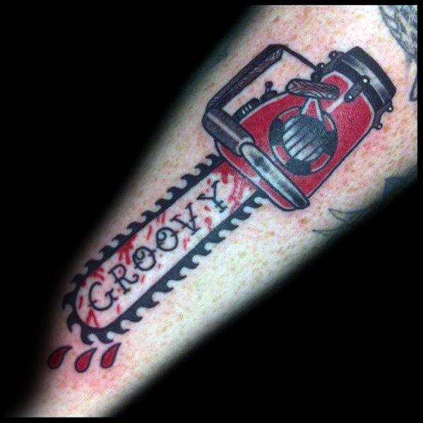 Stylized Evil Dead tattoo of a red chainsaw with dripping blood and the word "Groovy" carved into the blade in bold lettering.