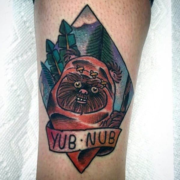 Cartoon-style Ewok tattoo framed in a diamond shape, with a red banner reading Yub Nub and a forest mountain backdrop.