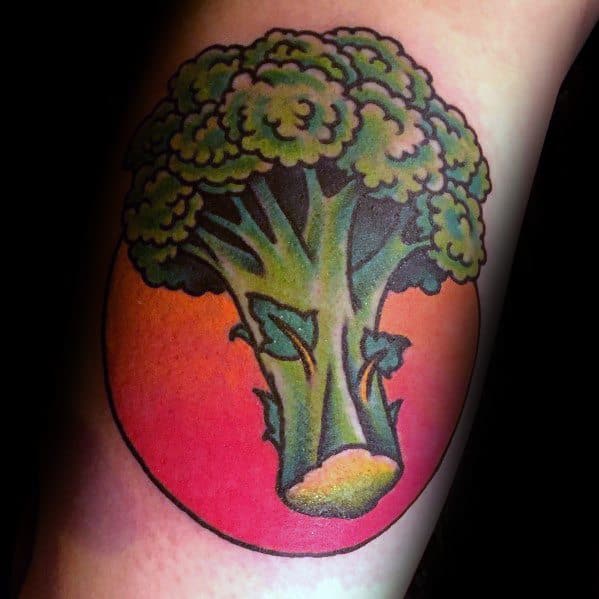 Vibrant broccoli tattoo with bold outlines and a sunset-inspired background, creating a striking contrast for a unique and artistic design.