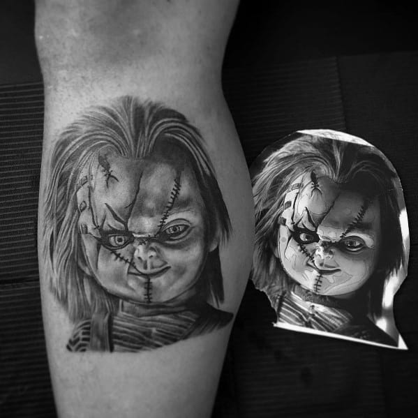 Black and grey Chucky tattoo with detailed shading, capturing his sinister grin, stitched face, and eerie expression for a chilling horror look.