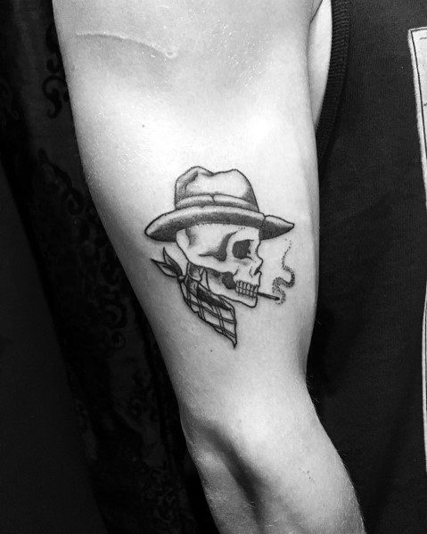 Black and gray tattoo of a cowboy skull wearing a hat, smoking a cigarette, with an arrow through its head and a bandana around its neck.