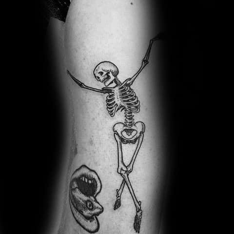 Dancing skeleton tattoo with crossed legs and raised arms, creating a playful and lively design with fine black ink details.