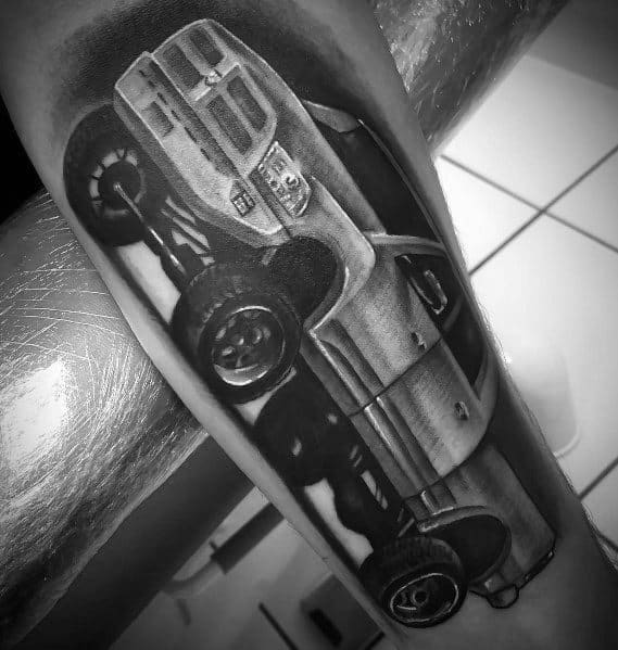 Realistic black and grey Dodge truck tattoo on forearm, showcasing fine details and shading for a bold and rugged design.