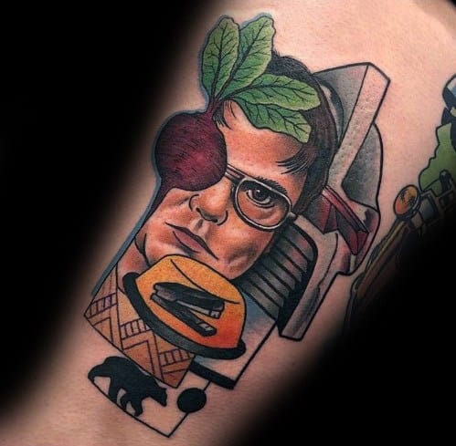 Colorful tattoo of Dwight Schrute with a beet as an eyepatch, surrounded by references like a stapler in Jell-O, a bear, and a sci-fi helmet.
