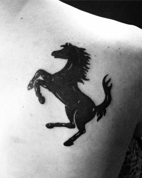 Black Ferrari horse tattoo on a man's shoulder, symbolizing speed, strength, and prestige.