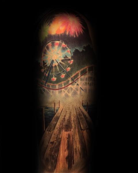 Vibrant Ferris wheel tattoo with a boardwalk, roller coaster, and fireworks in the night sky, creating a nostalgic amusement park scene.