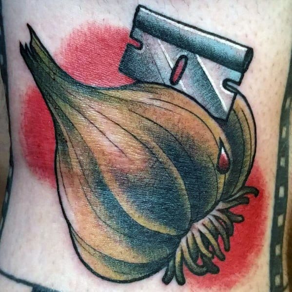 Bold garlic tattoo with a razor blade, featuring vibrant colors and striking shading, creating a unique and edgy design.