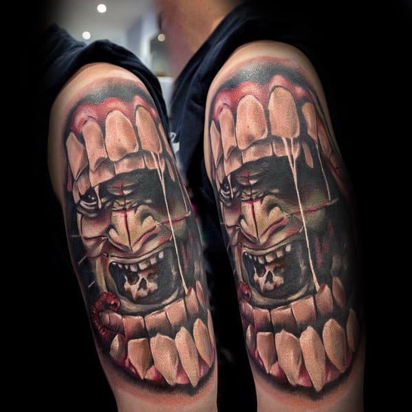 Terrifying *Hellraiser*-inspired tattoo featuring a screaming face trapped within a gory, tooth-lined frame, with realistic shading and textures.