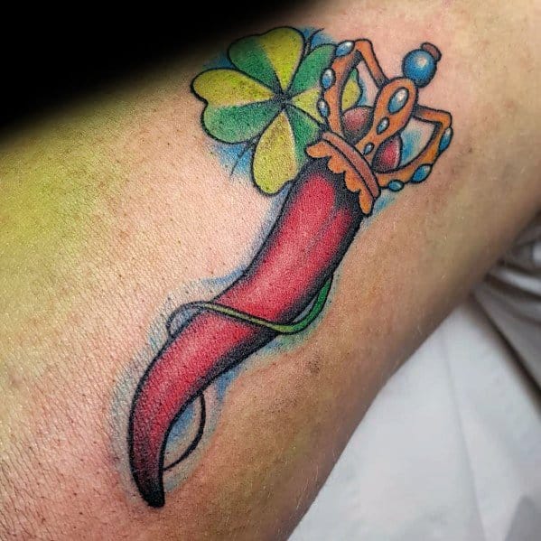 Vibrant Italian horn tattoo with a jeweled crown and four-leaf clover, symbolizing luck, protection, and prosperity.