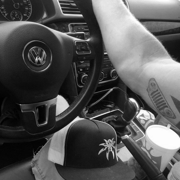 Minimalist Jeep tattoo on the forearm, featuring a simple yet bold design of the iconic Jeep grille with round headlights.