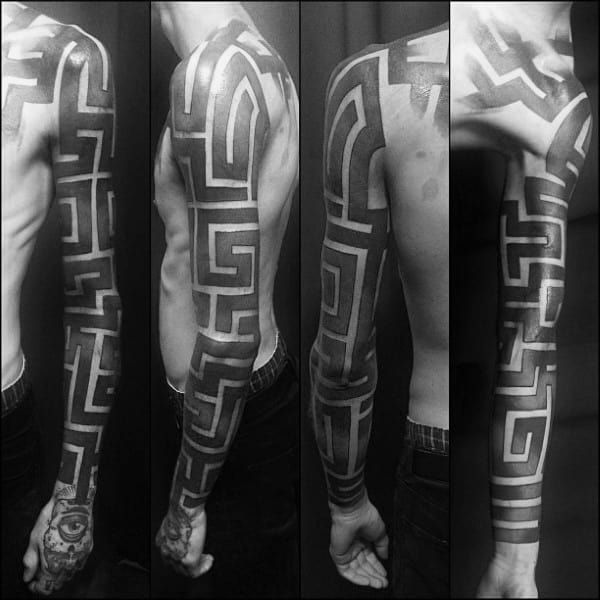 Full-sleeve blackwork labyrinth tattoo with bold geometric maze patterns wrapping around the arm, creating a striking and symmetrical design.