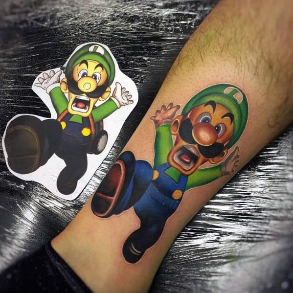 Realistic tattoo of Luigi in a shocked expression, mid-fall, with vibrant colors and detailed shading, placed on the leg next to its reference image.