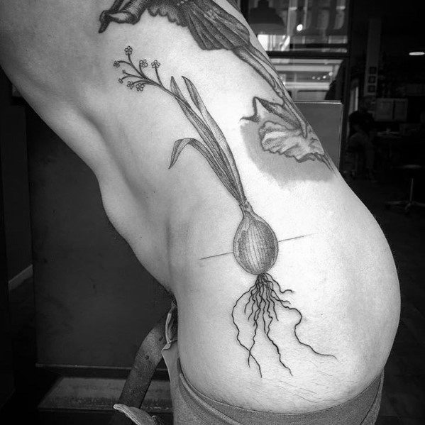 Black and grey onion tattoo on the ribcage, featuring fine line details with long sprouts and intricate roots for a botanical-inspired design.