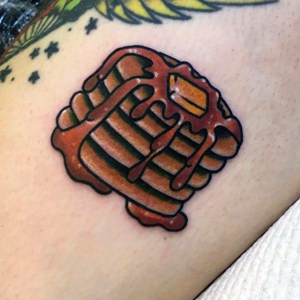 Bold pancake tattoo with thick syrup drips and a butter pat, featuring a cartoon-style design with dark outlines and vibrant shading.