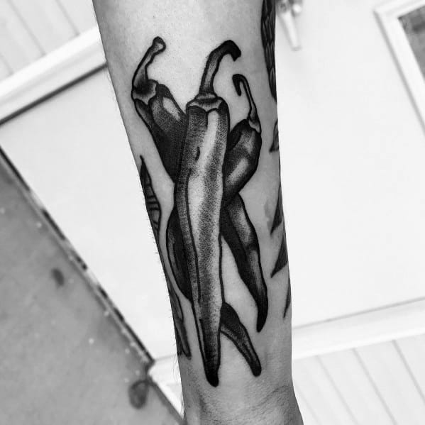 Black and grey chili pepper tattoo on the forearm with bold shading and fine details for a striking and realistic look.