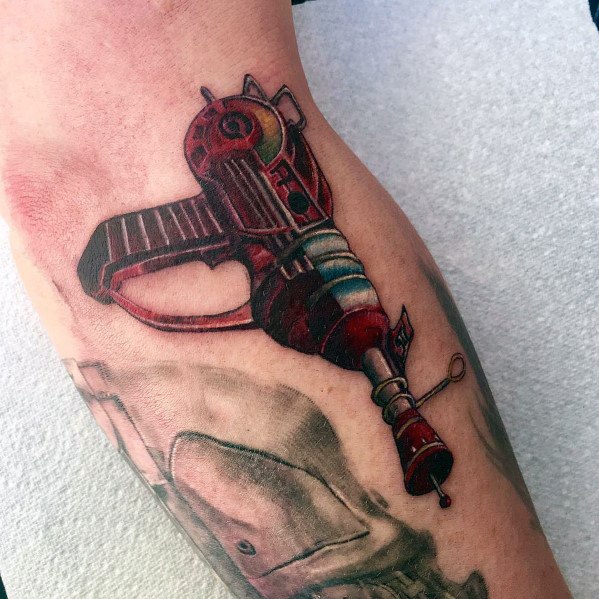 Realistic ray gun tattoo with a vintage sci-fi design, featuring rich shading, metallic details, and a bold red and blue color scheme.