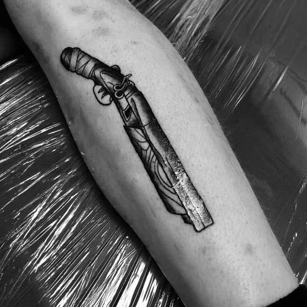 Black and grey flintlock shotgun tattoo with intricate detailing and bold shading, placed on the leg for a classic vintage firearm look.