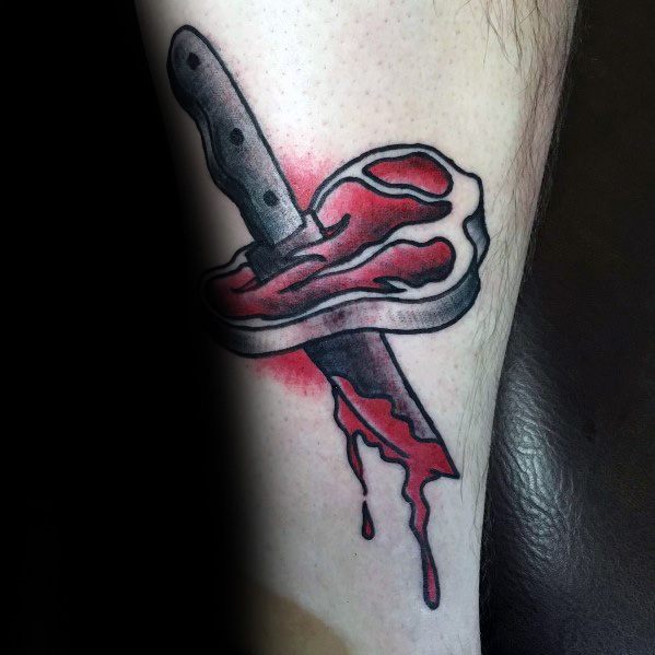 Tattoo of a steak pierced by a large knife, with dripping blood effect, creating a bold and intense design with strong shading and contrast