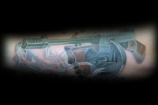 Realistic Tommy gun tattoo with detailed shading and smoke effects, featuring a bold and three-dimensional design for a dynamic firearm look.
