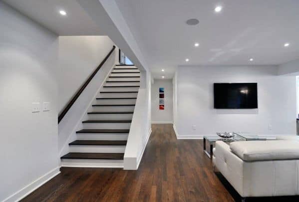 Minimalist staircase without railing in an open-plan living area with dark wood flooring.
