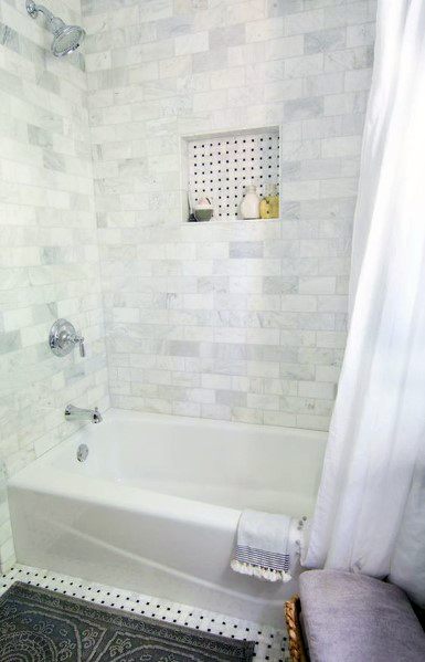 Bathroom with marble subway tile walls, built-in niche, and white bathtub.