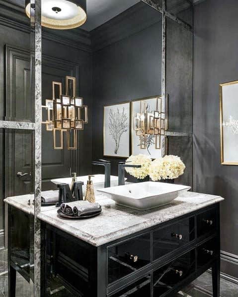 Elegant black bathroom with a marble countertop, modern chandelier, and gold accents.