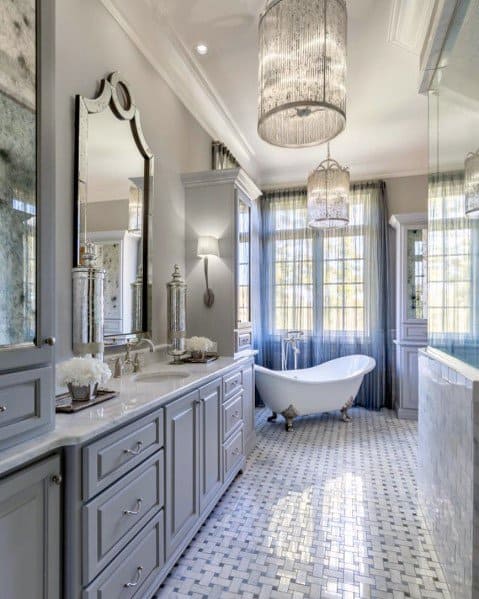 Elegant bathroom with freestanding tub, double chandeliers, and marble mosaic flooring.
