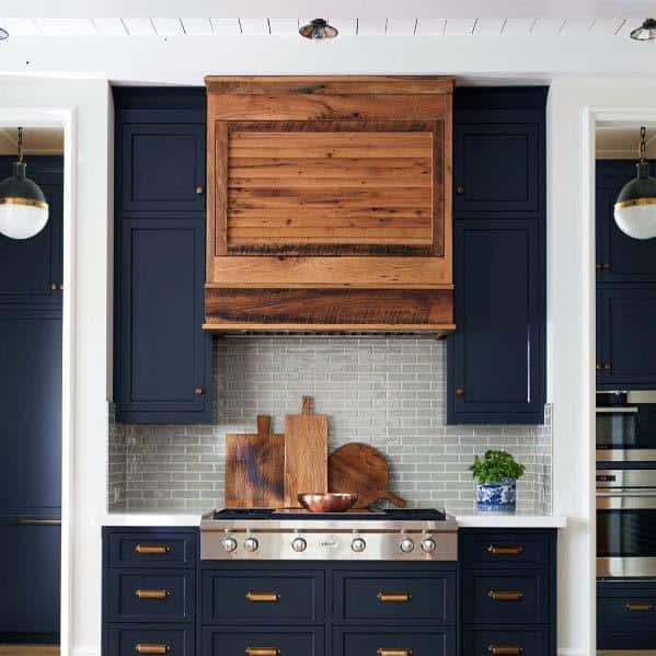 blue cabinet kitchen with wood hood and gray tile backsplash