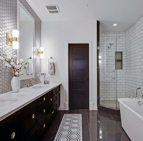 Country-style bathroom with dark vanity, hexagon tiles, and glass shower enclosure.