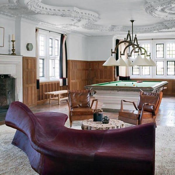 Elegant billiard room with ornate ceiling, leather seating, and a classic green felt table.