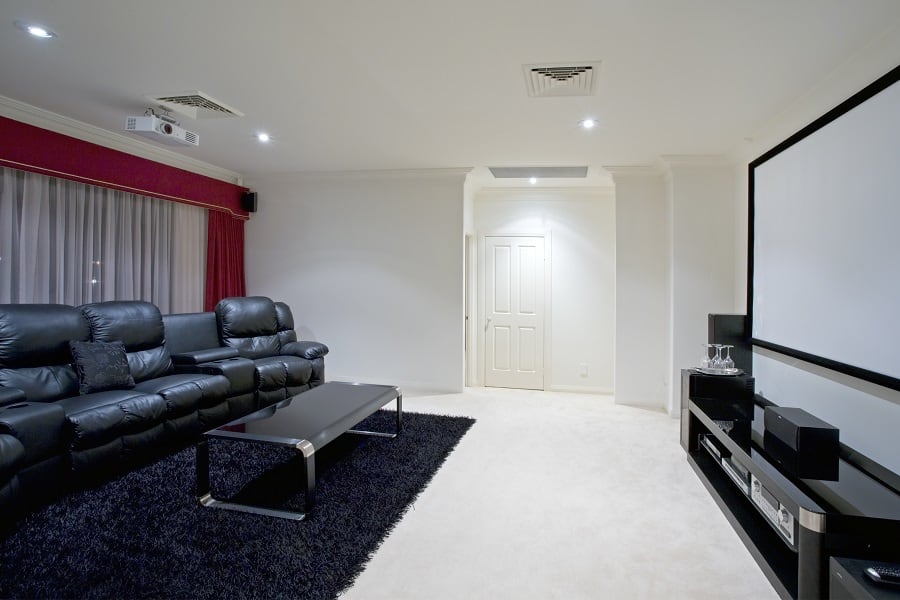 large white movie room with black leather sofas 