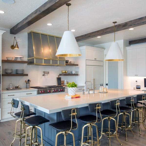 metallic framed kitchen hood with large white countertop island with seats
